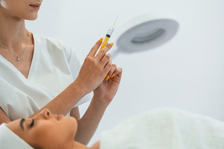 A nurse preparing a syringe beside a reclining client — med spa in McAllen and Pharr, TX